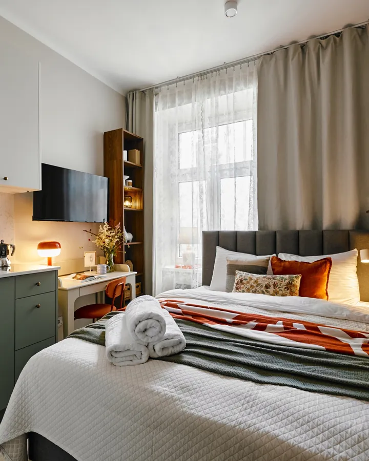 Studio with the bed, kitchenette and a lace-curtained window